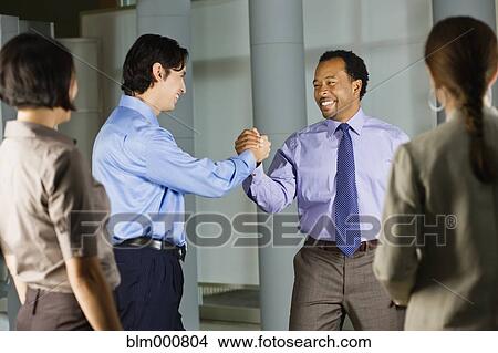 Picture - Multi-ethnic co-workers shaking hands in office. Fotosearch