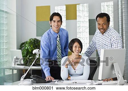 Stock Image - Multi-ethnic co-workers working in office. Fotosearch
