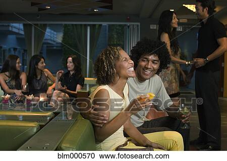 Stock Image - Multi-ethnic couple drinking cocktails in nightclub. Fotosearch