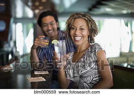 Stock Photo - Multi-ethnic couple drinking in nightclub. Fotosearch