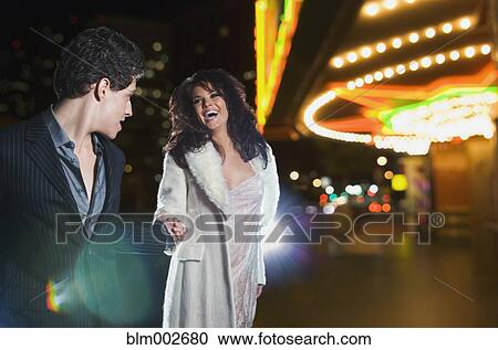 Multi-ethnic couple holding hands and laughing outside nightclub View Large Photo Image Stock Image - Multi-ethnic couple holding hands and laughing outside nightclub. Fotosearch