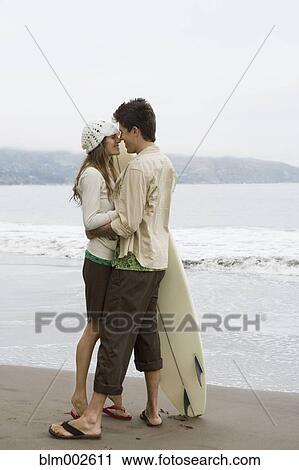 Stock Image - Multi-ethnic couple hugging at beach. Fotosearch
