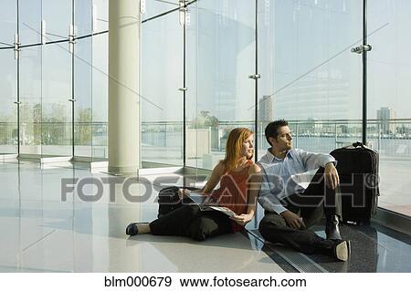 Multi-ethnic couple sitting in floor at airport View Large Photo Image Stock Photo - Multi-ethnic couple sitting in floor at airport. Fotosearch