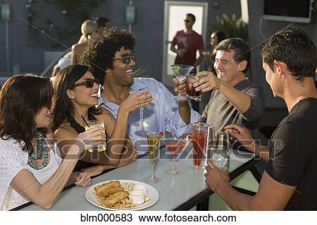 Multi-ethnic friends drinking cocktails poolside View Large Photo Image Stock Image - Multi-ethnic friends drinking cocktails poolside. Fotosearch