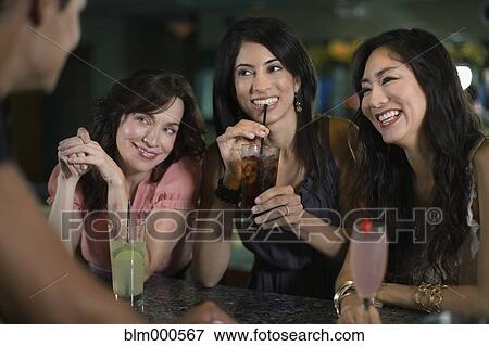 Multi-ethnic friends drinking cocktails in nightclub View Large Photo Image Stock Photo - Multi-ethnic friends drinking cocktails in nightclub. Fotosearch