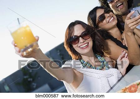 Stock Photo - Multi-ethnic friends drinking cocktails. Fotosearch