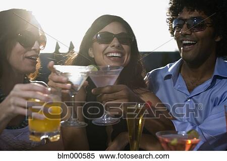 Stock Photography - Multi-ethnic friends drinking cocktails. Fotosearch