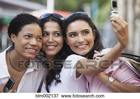 Stock Photo - Multi-ethnic friends taking own photograph. Fotosearch