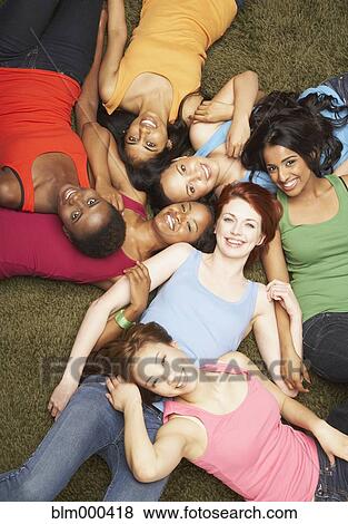 Stock Photo - Multi-ethnic women laying together on carpet. Fotosearch