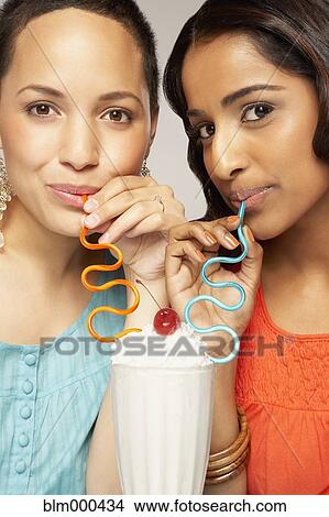 Picture - Multi-ethnic women sharing milkshake. Fotosearch