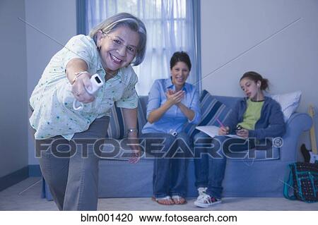 Stock Image - Multi-generational family playing video game. Fotosearch