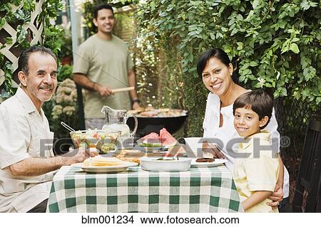 Picture - Multi-generational Hispanic family eating on patio. Fotosearch