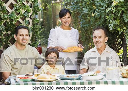 Stock Image - Multi-generational Hispanic family eating on patio. Fotosearch