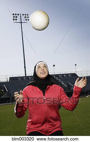 Stock Image - Muslim teenager practicing with soccer ball. Fotosearch