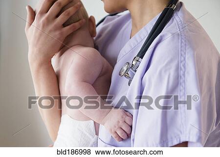 Stock Photo - Nurse holding baby in hospital. Fotosearch