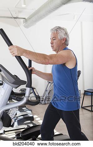 Older Hispanic man using elliptical machine in gym View Large Photo Image Stock Image - Older Hispanic man using elliptical machine in gym. Fotosearch
