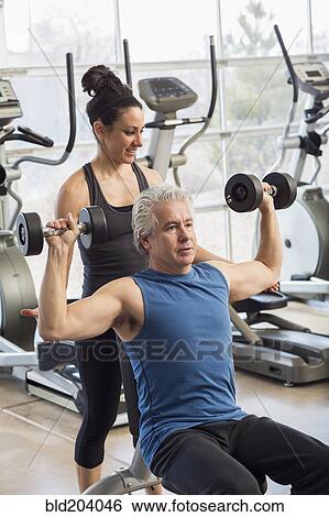 Older Hispanic man working with trainer in gym View Large Photo Image Stock Photograph - Older Hispanic man working with trainer in gym. Fotosearch