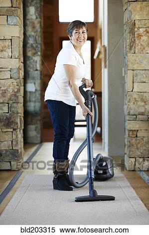 Older Hispanic woman vacuuming carpet View Large Photo Image Stock Photography - Older Hispanic woman vacuuming carpet. Fotosearch