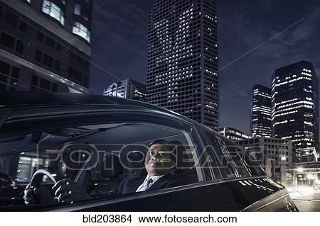 Picture - Pacific Islander businessman driving on city street. Fotosearch