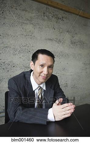 Stock Image - Pacific Islander businessman sitting at table. Fotosearch