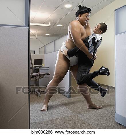 Stock Photograph - Pacific Islander sumo wrestler lifting businessman in office. Fotosearch
