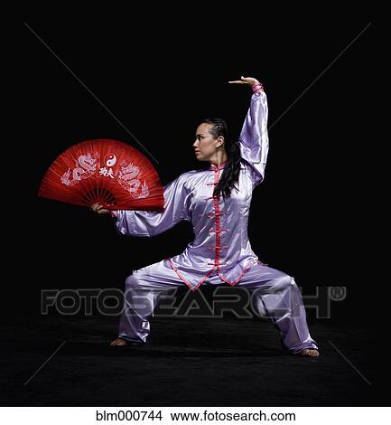 Picture - Pacific Islander woman practicing martial arts with fan. Fotosearch