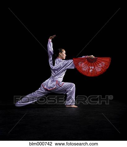 Stock Image - Pacific Islander woman practicing martial arts with fan. Fotosearch