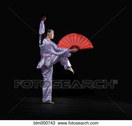 Stock Image - Pacific Islander woman practicing martial arts with fan. Fotosearch