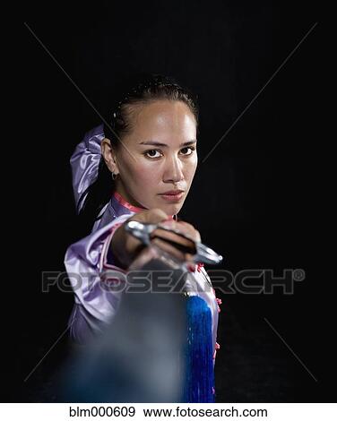 Stock Photo - Pacific Islander woman practicing martial arts with sword. Fotosearch