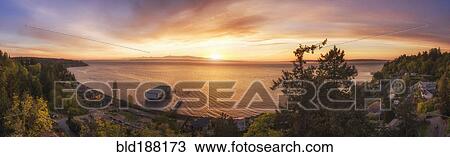 Stock Image - Panoramic view of sunset over lake in remote landscape. Fotosearch