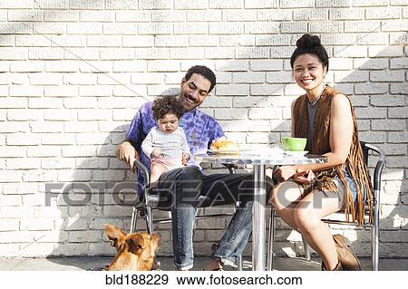 Stock Photo - Parents eating with baby son at outdoor cafe. Fotosearch