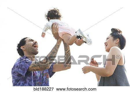 Stock Photo - Parents playing with baby son outdoors. Fotosearch