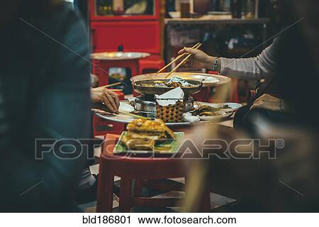 Stock Image - People eating with chopsticks in restaurant. Fotosearch