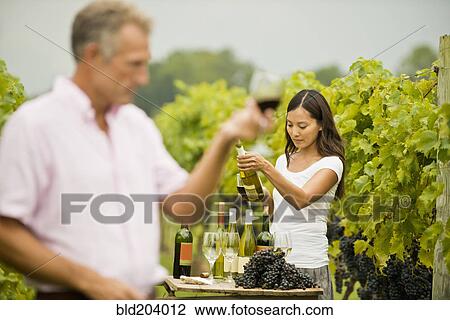 Stock Image - People tasting wine in vineyard. Fotosearch