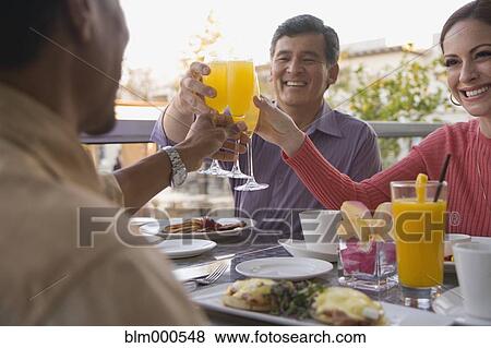 Stock Photo - People toasting over breakfast in restaurant. Fotosearch