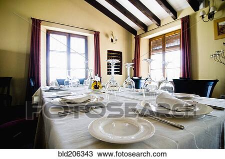 Stock Image - Place settings on table in luxury dining room. Fotosearch