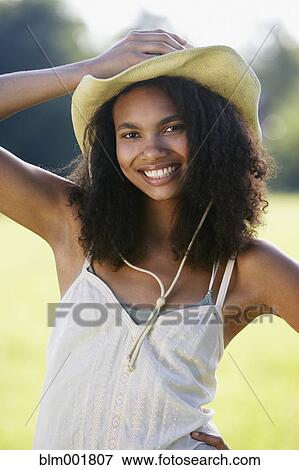 Stock Photo - Portrait of African woman wearing straw hat outdoors. Fotosearch