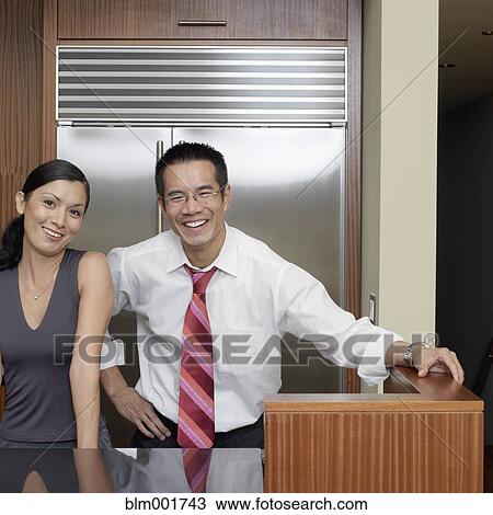 Stock Image - Portrait of Asian couple in kitchen. Fotosearch