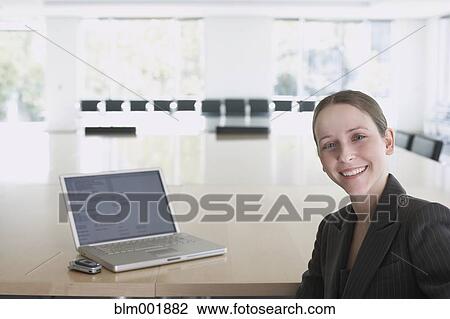Stock Image - Portrait of businesswoman next to laptop. Fotosearch
