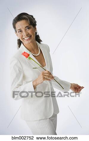 Stock Image - Portrait of Hispanic woman holding rose. Fotosearch