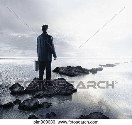 Stock Photograph - Portuguese businessman standing on rocks in water. Fotosearch