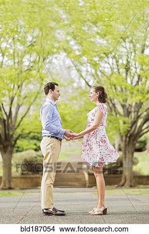 Picture - Pregnant Caucasian couple holding hands outdoors. Fotosearch