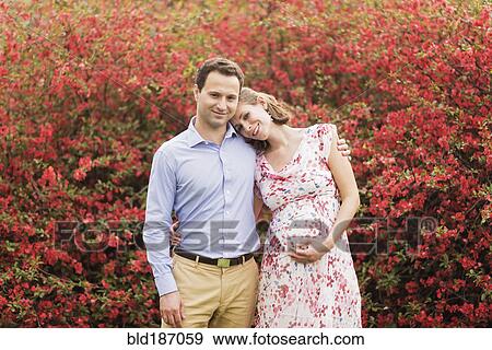 Stock Photo - Pregnant Caucasian couple hugging outdoors. Fotosearch