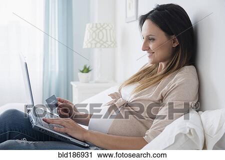 Stock Image - Pregnant Caucasian shopping online. Fotosearch