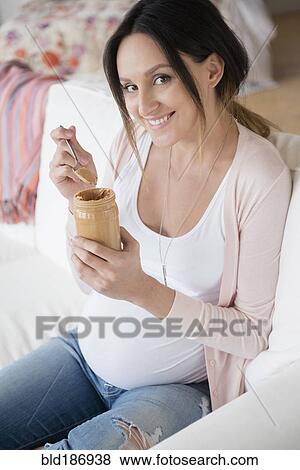 Pregnant Caucasian woman eating peanut butter from jar View Large Photo Image Stock Photo - Pregnant Caucasian woman eating peanut butter from jar. Fotosearch