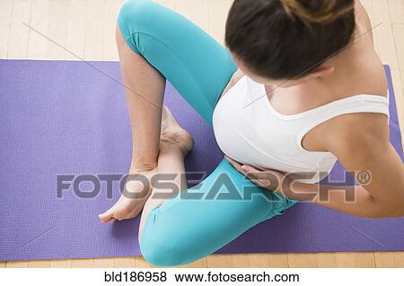 Stock Photo - Pregnant Caucasian woman holding belly on yoga mat. Fotosearch
