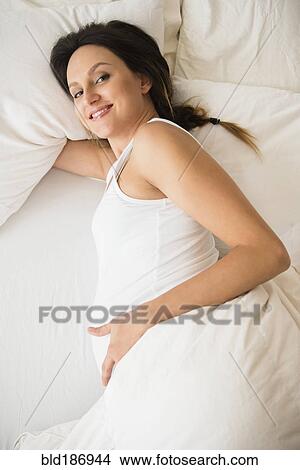 Pregnant Caucasian woman laying on bed View Large Photo Image Picture - Pregnant Caucasian woman laying on bed. Fotosearch