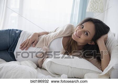 Pregnant Caucasian woman laying on bed View Large Photo Image Stock Image - Pregnant Caucasian woman laying on bed. Fotosearch