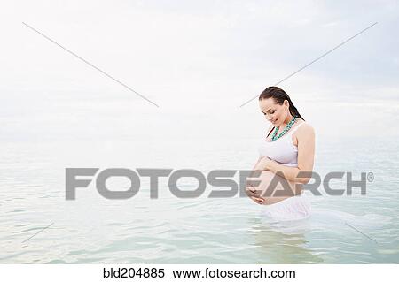Stock Photography - Pregnant Caucasian woman standing in water. Fotosearch