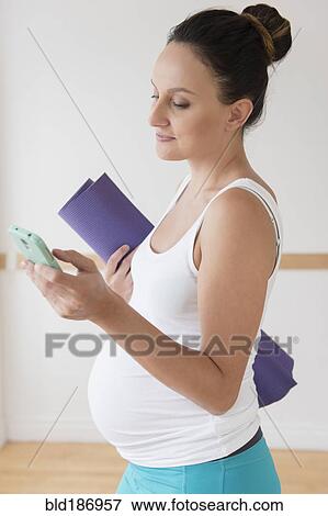 Stock Photo - Pregnant Caucasian woman using cell phone. Fotosearch